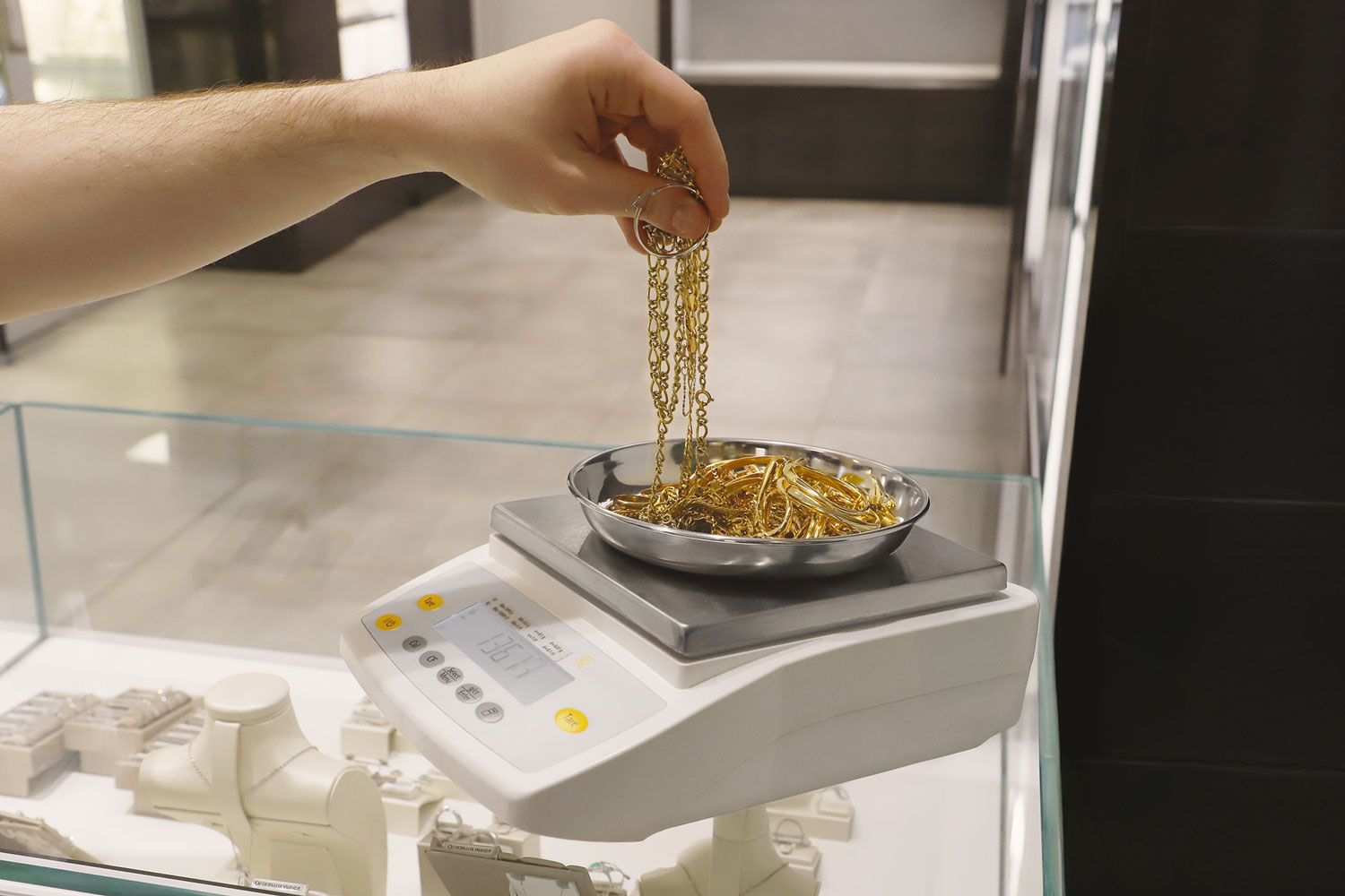 Un gioielliere pesa dei gioielli in oro giallo con una bilancia professionale per effettuare la valutazione del prezzo di acquisto