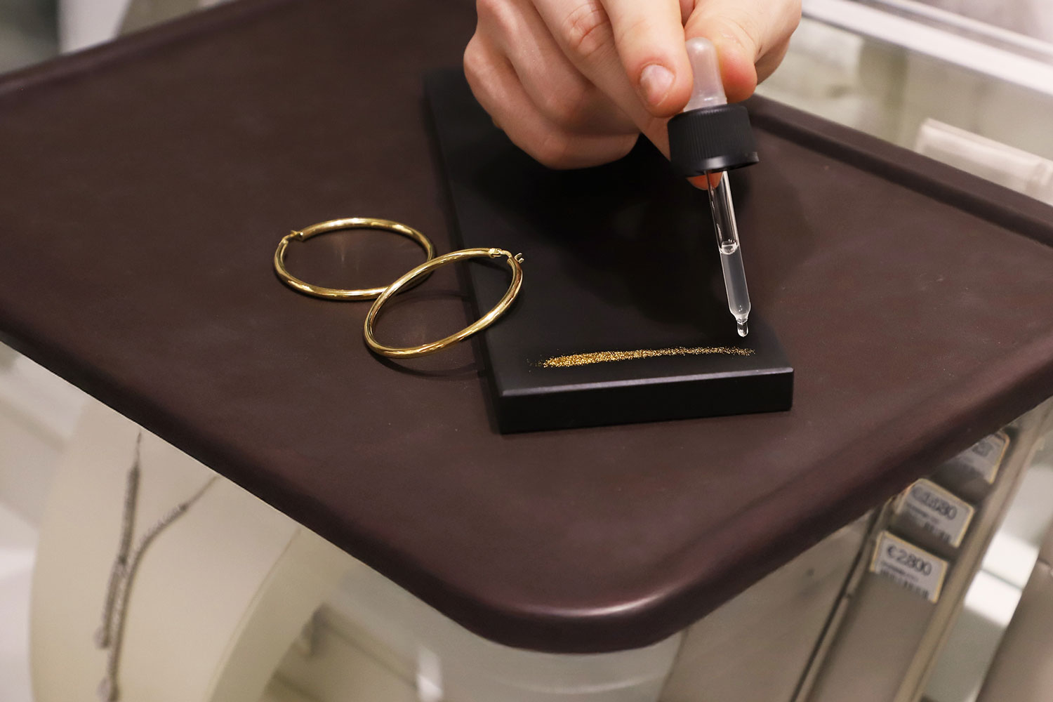 Un operatore svolge il test della pietra di paragone con l'acido per determinare l'autenticit&agrave; e la caratura dell'oro di alcuni orecchini